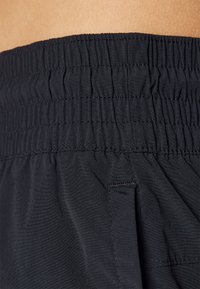 Cintura elástica negra con textura fruncida, parte de un diseño de tela ligera, que presenta un bolsillo lateral y una superficie suave.