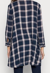 Marinblå och ljusrosa rutiga tunika med långa ärmar och knappmanschetter; lätt vikt tyg, avslappnad passform och böjd nederkant.