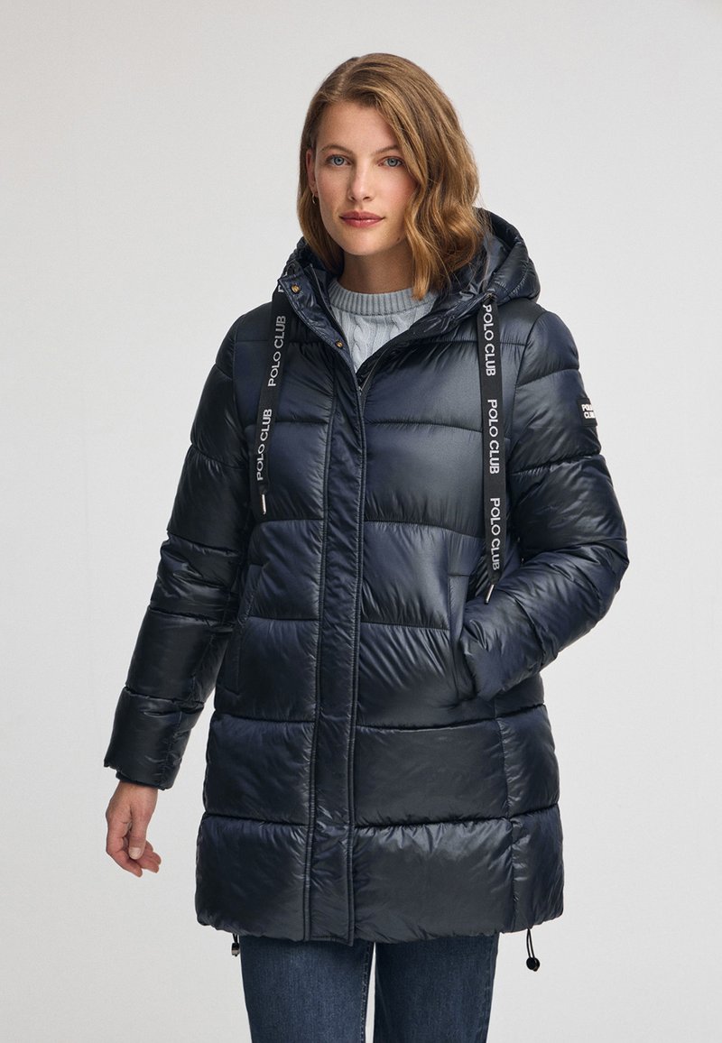 Marinblå pufferjacka med huva, quiltat mönster, två sidofickor och dragskoaccenter. Polyester material, slät textur och dragkedja fram.