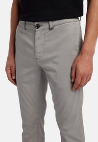 Helle graue Baumwollhose mit geradem Schnitt, ausgestattet mit einem Frontknopfverschluss, Seitentaschen und dezenten Steppnähten.