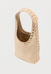 Sac beige en matière douce, doté d'un dessus arrondi, de détails dorés cloutés le long des bords, et d'une ouverture supérieure pour un accès facile.