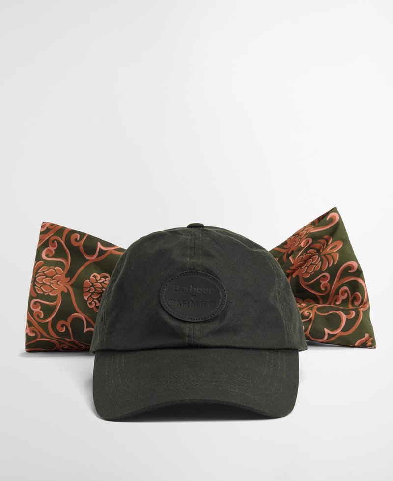 Boné de algodão verde escuro com aba arredondada, apresentando um patch de logotipo circular preto. Um lenço de seda reversível com um padrão floral em coral e verde está atrás.