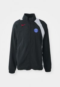 Black lightweight jacket with a high collar, featuring a white panel, red Nike logo, and blue PSG emblem. Elastic cuffs and zipper closure.