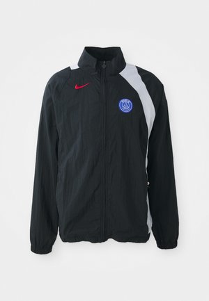 Črna lahka jakna z visokim ovratnikom, z belim delom, rdečim logotipom Nike in modrim grbom PSG. Elastični manšeti in zadrga.