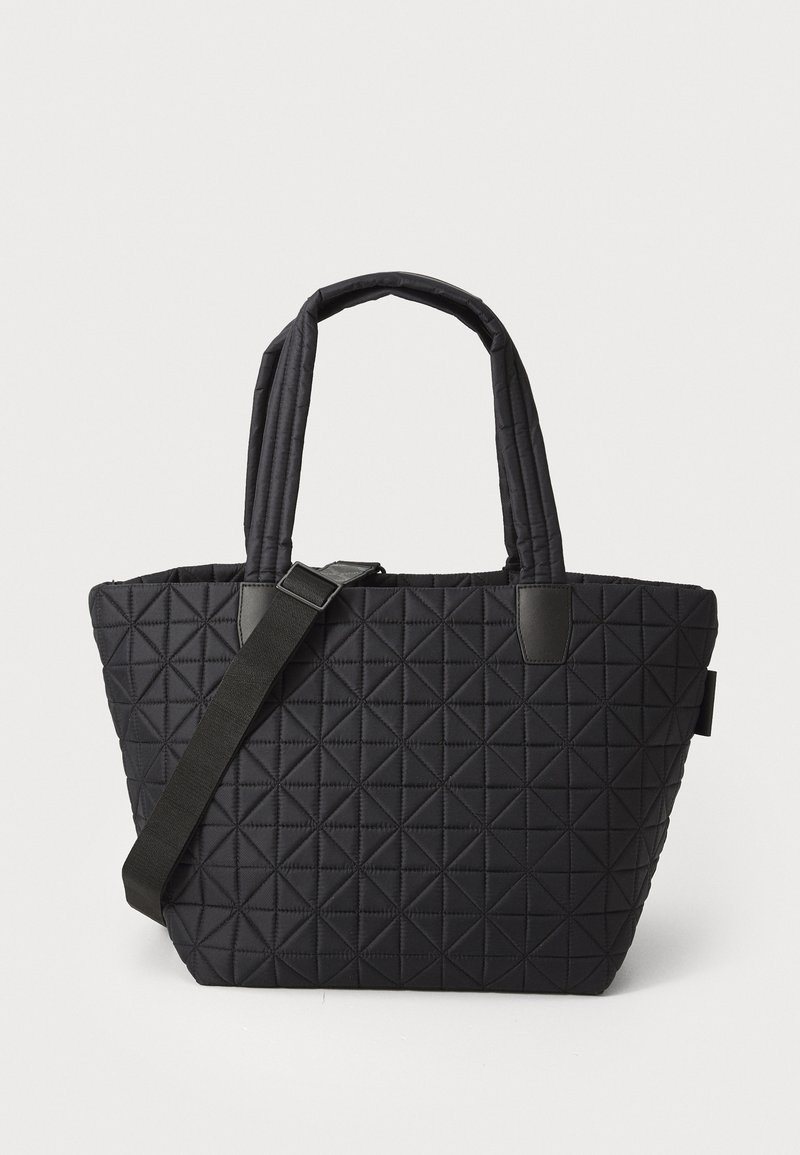Svart quilted tote-bag med geometrisk mønster, utstyrt med to tekstilhåndtak og justerbar skulderstropp. Glatt tekstur og strukturert form.