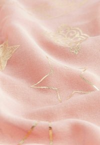 Tissu rose clair présentant des motifs d'étoiles et de couronnes dorées, affichant un tissage doux et texturé avec un léger éclat provenant des accents métalliques.