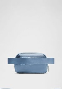 Bolso cruzado de nylon de color azul claro con cierre de cremallera, textura suave y cinturón de tela ancho, que cuenta con un compartimento de doble cremallera en la parte superior.