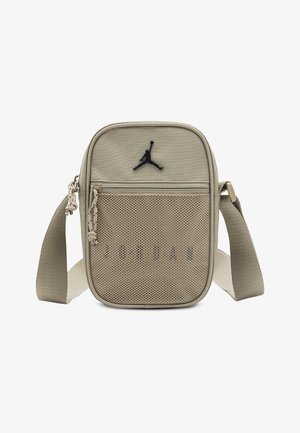 Geantă crossbody dreptunghiulară bej, cu curea reglabilă, buzunar frontal cu fermoar din plasă și logo Jumpman negru în centrul de sus.