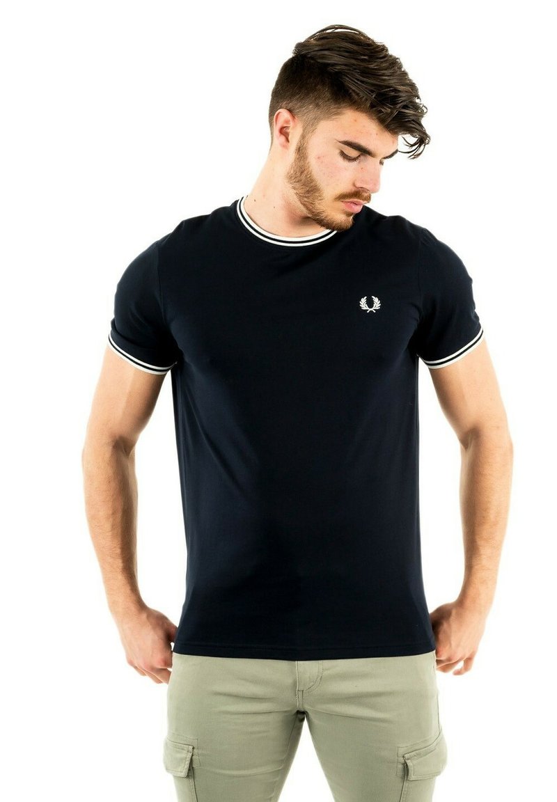 Camiseta de manga corta azul marino con cuello y puños de canalé blancos, que presenta un pequeño emblema en el pecho y un diseño ajustado.