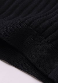 Μαύρο ριμπ πλεκτό ύφασμα με υφή; διαθέτει διακριτικό λογότυπο στην άκρη. Ομαλή υφή με λεπτομέρεια διπλωμένου τελειώματος.