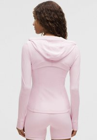 Sudadera rosa ajustada con mangas largas y capucha con cordón. Tejido suave con detalles de costura que recorren la espalda y los lados.
