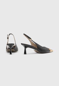 Črne usnjene sandale s koničastim nosom, z zlatimi detajli in majhnimi črnimi stiletto petami. Narejene so v elegantnem slogu in imajo gladko teksturo.