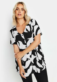 Kurzärmlige Bluse in Schwarz und Weiß mit V-Ausschnitt, Knopfverschluss und abstrakten Mustern in verschiedenen Formen. Leichter Stoff, lockere Passform.