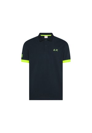 Camisa polo azul marino con ribete en el cuello de color amarillo neón, puños de las mangas, "08" en la manga izquierda, y pequeño logo geométrico en el pecho izquierdo.