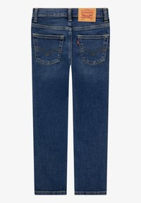 Tummansiniset farkut, joissa on klassinen viiden taskun malli, merkitty nahkalappu ja tikatut yksityiskohdat takataskuissa.