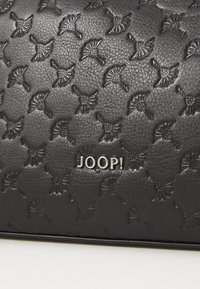 Pelle nera testurizzata con un motivo ripetuto, con un logo "JOOP!" argentato ben visibile sul davanti, che mette in risalto un accessorio elegante.
