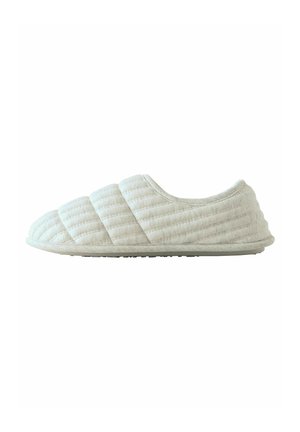 Gequilte witte slipper met een ronde neus, zachte stoffen bovenkant en een gestructureerde zool. Heeft opvallende stiksels en een instapontwerp.