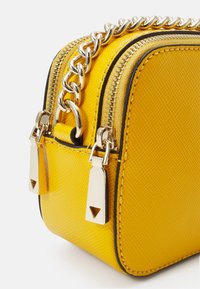 Piccolo borsa gialla rettangolare con materiale testurizzato, tracolla in catena dorata, doppia cerniera e dettagli metallici. Presenta un design strutturato.