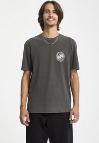 Grå bomulds T-shirt med rund hals og korte ærmer. Har et hvidt grafisk logo på venstre bryst og en afslappet pasform.