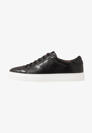 Black leather sneaker with a smooth finish, white rubber sole, lace-up design, and embossed logo on the side. Classic, minimalist aesthetic.