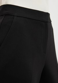 Černé kalhoty s hladkým povrchem, úzkým střihem, bočními kapsami a rovný pas, navržené pro elegantní vzhled.