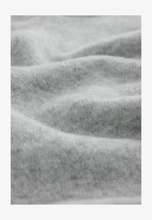 Hallidekootud kude pehme ja tekstuurse pinnaga, kust nähtuvad õrnad voldid ja peen heatheri muster.