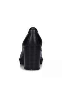 Scarpa nera in pelle con tacco, dalla punta arrotondata, caratterizzata da un tacco spesso e una superficie liscia, vista da dietro.