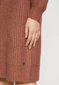 Abito lavorato a maglia in una calda tonalità di rosa polveroso, con texture a coste, maniche lunghe e un dettaglio logo in metallo nero all'orlo.
