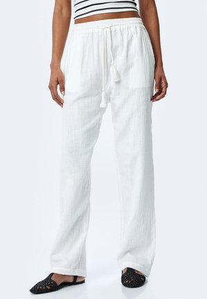 Hvide, letvægts, strukturerede bukser med elastisk talje og snortræk. Sammen med sorte, vævede flade sko.