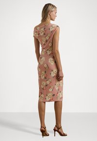 Blomstretrykt knelengdress i myk rosa. Har korte ermer og en tettsittende silhuett. Teksturert stoff med store blomster i krem og rødt.