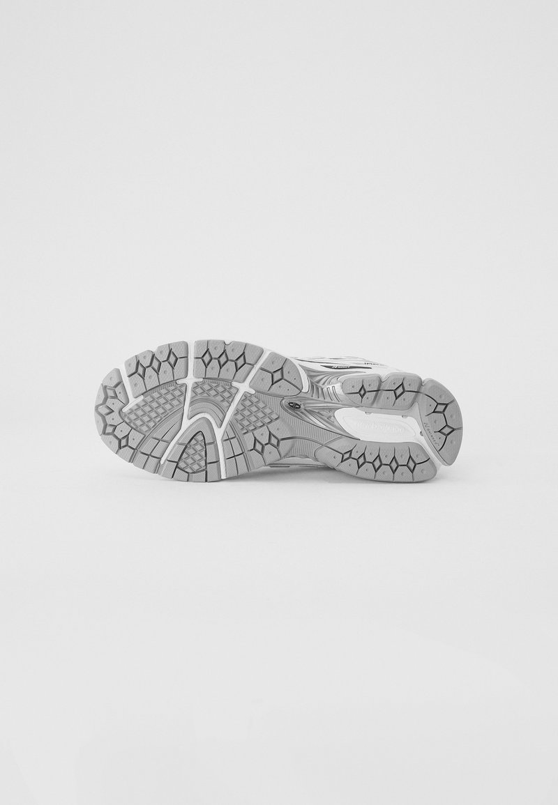 Suola di scarpa da corsa in grigio e bianco. Presenta gomma testurizzata con un motivo a battistrada, scanalature per la trazione e un'area del tallone rinforzata.