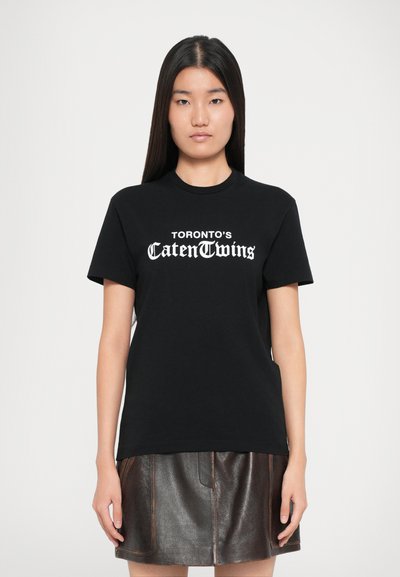 Μαύρο βαμβακερό t-shirt με κοντά μανίκια που έχει άσπρο κείμενο που γράφει "TORONTO'S CattenTwins" μπροστά, στρογγυλή λαιμόκοψη, κλασική εφαρμογή.