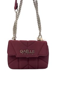 Borsa a tracolla quilted color mogano con una catena argentata e il logo "Gaëlle Paris" sul fronte. Presenta un materiale testurizzato e una forma strutturata.