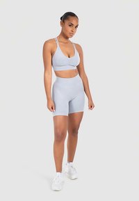 Vaaleansininen urheilurintaliivien ja korkeavyötäröisten shortsien setti, valmistettu pehmeästä, joustavasta materiaalista. Minimalistinen muotoilu ja saumaton rakenne.