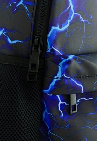 Schwarzer und blauer Rucksackstoff mit Blitzmuster. Verfügt über einen schwarzen Reißverschluss und eine Netzseite, die ein strukturiertes, robustes Design zeigt.