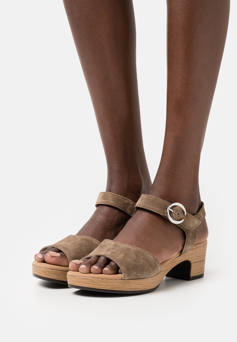 Bruna mockaskinnsandaler med klack, öppen tå, ankelsnodd med en silverspänne och en texturerad träplattform.