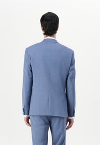 Lichtblauwe blazer van een geweven stof, met een enkele split aan de achterkant en knoopaccenten op de mouwen, gezien vanaf de achterkant.