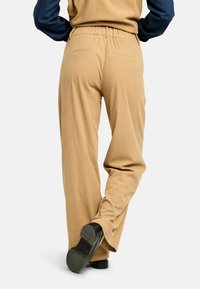 Világosbarna kordbársony nadrág laza szabással, elasztikus derékrésszel és hátsó zsebekkel. Texturált anyag széles lábakkal és látható varrással.