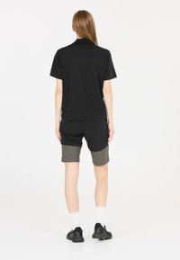 Svart t-shirt med kort ärm i kombination med svarta och olivgröna shorts. Outfiten har en enkel design med enfärgade nyanser och en avslappnad passform.