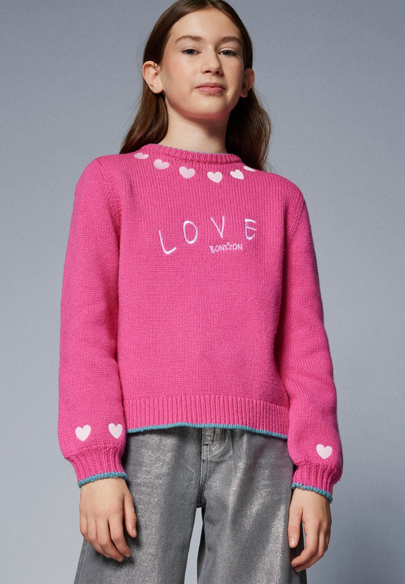Pink knit sweater featuring a heart pattern along the neckline and at the cuffs. The word "LOVE" is embroidered on the front in white.
