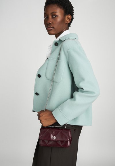 Mint-green wool jacket with black buttons and a chest pocket. Burgundy leather quilted handbag with silver chain strap and logo detail.