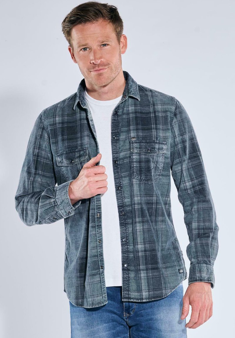 Grau-schwarzes kariertes Flanellhemd mit zwei Brusttaschen, Knopfverschluss und sichtbaren Steppnähten, getragen über einem weißen T-Shirt.