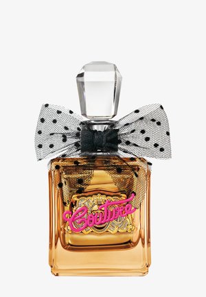 Quadratische Bernstein-Glas-Parfümflasche mit einem klaren, facettierten Deckel, einer schwarzen Netzschleife mit Punkten und pinkem "Couture"-Text auf einem goldenen Etikett.