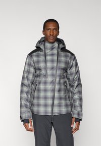 Chaqueta de cuadros para hombre en tonos gris y verde con capucha, con detalles negros en los hombros, bolsillos con cremallera y superficie texturizada.