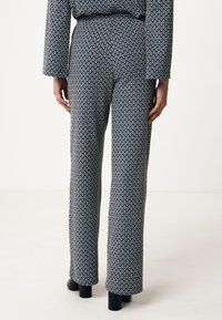 Broek in een geometrisch blauw en zwart patroon, met een wijde pijpdesign, een gladde textuur, een elastische tailleband en effen zwarte schoenen.