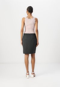 Světle růžový žebrovaný top na ramínka s krajkovým lemem na okrajích, doplněný tmavě šedou sukní ke kolenům s elastickým pasem a dvěma kapsami.