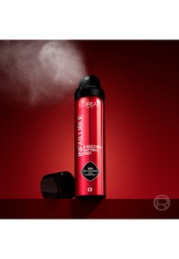 Spray rouge L'Oréal Paris Infaillible 3-Second Setting Mist diffusant une brume, bouchon noir retiré, fond rouge.