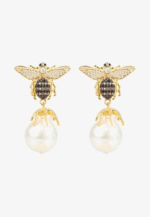 Boucles d'oreilles en ton or avec un design d'abeille orné d'accents en cristal noir et blanc, surmontées d'une grosse perle blanche brillante.