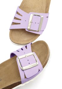 Purple suede sandals with cutout design, silver metal buckle, and tan cushioned footbed. Lightweight white sole with textured finish.