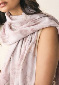 Šviesiai rožinė gėlių rašto skara, pagaminta iš minkštos medžiagos, drapiruota ant pečių su subtiliais raštais ir lygiu paviršiumi.